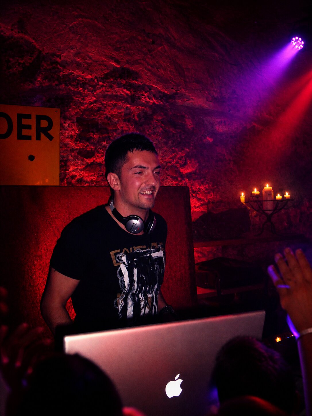 DJ Monaco dans une cave voûtée éclairée en rouge, ambiance intime aux chandelles