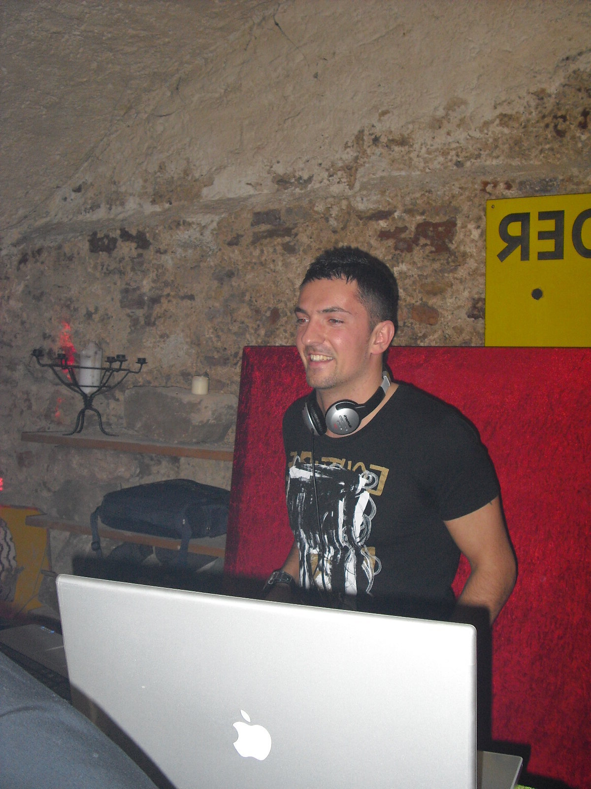 DJ Monaco souriant aux platines dans une cave voûtée en pierre