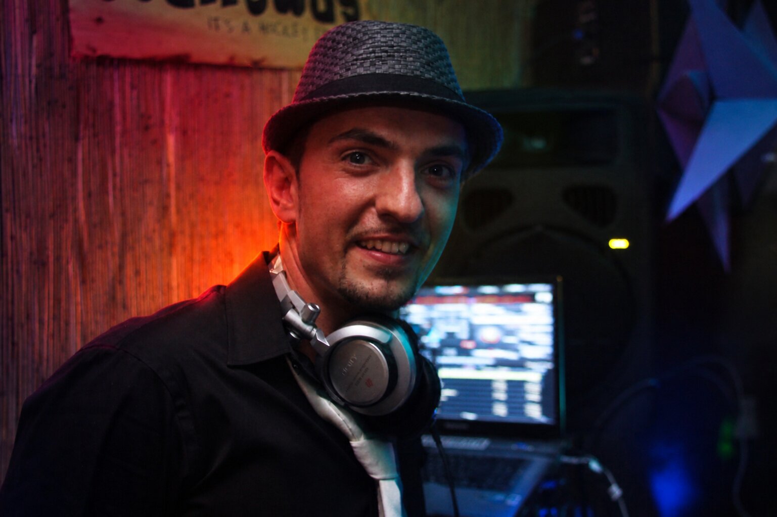 DJ Monaco avec chapeau fedora et casque audio en club