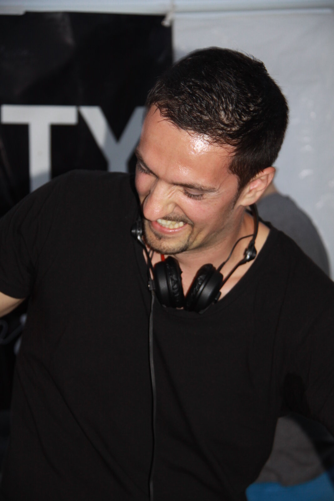 DJ Monaco en t-shirt noir, casque autour du cou, ambiance fin de soirée